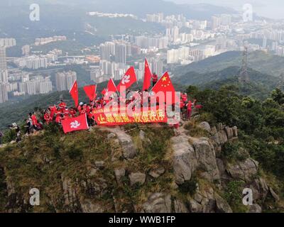 Hong Kong, Cina. Xiv Sep, 2019. Onda residenti della Cina di bandiera nazionale e la bandiera della regione amministrativa speciale di Hong Kong (SAR) al picco di Lion Rock a Hong Kong, Cina del sud, Sett. 14, 2019. Oltre 100 agli abitanti di Hong Kong sventolate le bandiere e striscioni terrà la lettura "celebrando in occasione del settantesimo anniversario della fondazione della Repubblica popolare cinese " e " topping violenza, terminando il caos e il ripristino dell'ordine' qui il sabato. Credito: Lui Siu Wai/Xinhua/Alamy Live News Foto Stock