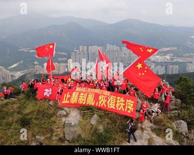 Hong Kong, Cina. Xiv Sep, 2019. Onda residenti della Cina di bandiera nazionale e la bandiera della regione amministrativa speciale di Hong Kong (SAR) al picco di Lion Rock a Hong Kong, Cina del sud, Sett. 14, 2019. Oltre 100 agli abitanti di Hong Kong sventolate le bandiere e striscioni terrà la lettura "celebrando in occasione del settantesimo anniversario della fondazione della Repubblica popolare cinese " e " topping violenza, terminando il caos e il ripristino dell'ordine' qui il sabato. Credito: Lui Siu Wai/Xinhua/Alamy Live News Foto Stock