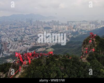 Hong Kong, Cina. Xiv Sep, 2019. Onda residenti della Cina di bandiera nazionale e la bandiera della regione amministrativa speciale di Hong Kong (SAR) al picco di Lion Rock a Hong Kong, Cina del sud, Sett. 14, 2019. Oltre 100 agli abitanti di Hong Kong sventolate le bandiere e striscioni terrà la lettura "celebrando in occasione del settantesimo anniversario della fondazione della Repubblica popolare cinese " e " topping violenza, terminando il caos e il ripristino dell'ordine' qui il sabato. Credito: Lui Siu Wai/Xinhua/Alamy Live News Foto Stock