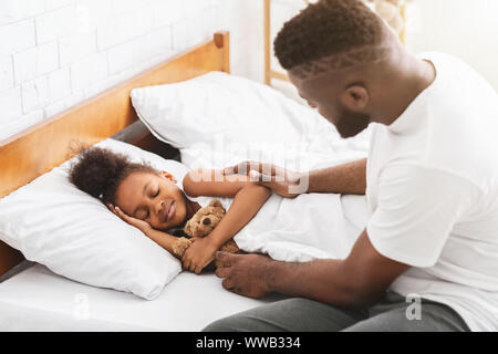 La cura di papà africane mettendo la sua piccola figlia dormire Foto Stock