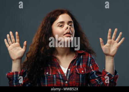 Una donna divertente volto schiacciato sul vetro trasparente Foto Stock