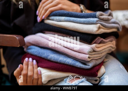 Un vasto assortimento di cappelli in mani femminili. Il concetto di moda, stilista, sfondo, vestiti a maglia. Foto Stock