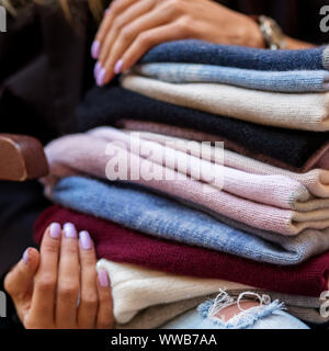 Un vasto assortimento di cappelli in mani femminili. Square. Il concetto di moda, stilista, sfondo, vestiti a maglia. Foto Stock