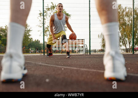 Maschio di giocatore di basket con sfera mostra la sua abilità Foto Stock