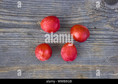 Ripe rosso ciliegia prugne sul vecchio sfondo di legno, close-up. Foto Stock