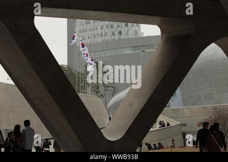 Bandiere nazionali sono sventolando nella brezza incorniciato da colonne di forma triangolare del Museo del Design di Zaha Hadid, Dongdaemon, Seoul, Corea del Sud. Foto Stock