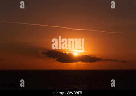 Raggi di sole dietro una nuvola durante il tramonto sulla costa adriatica, Puglia, Italia Foto Stock