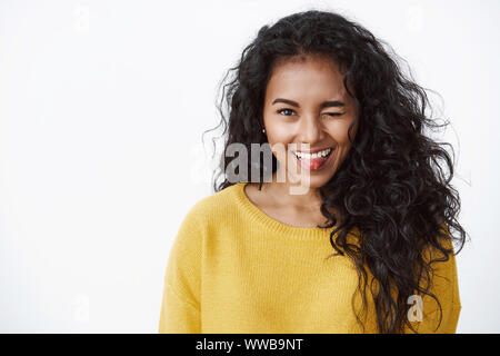 Divertente, entusiasta african american curly-ragazza dai capelli in Giallo autunno maglione silly winking e che mostra la linguetta con la cute espressione flirty, in piedi Foto Stock