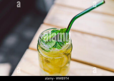 La limonata cocktail guarnito con limone e menta sulla tabella. bevanda analcolica in vintage mason vasetto in vetro. bibita al limone in vetro con paglia di metallo Foto Stock