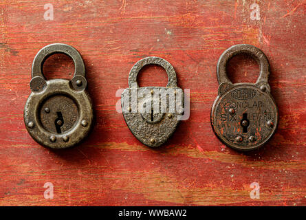 3 rusty antico si blocca su un rosso spiovente di legno verniciato bordo. Foto Stock