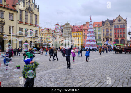 Wroclaw, Polonia Novembre 17, 2017. I Bambini a caccia di bolle di sapone in città la piazza principale, tutte decorate durante l annuale mercatino di Natale Foto Stock
