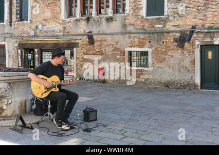 Venezia, Italia - 20 Aprile 2019: il giovane artista di strada a suonare la chitarra in un vecchio square Foto Stock