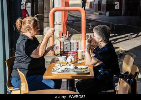 Una donna di mezza età e la sua anziana madre parlando pur avendo un caffè in un coffee shop Foto Stock
