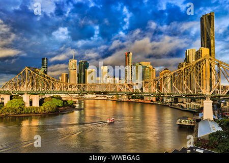 Storia ponte attraverso il fiume Brisbane davanti la città di Brisbane CBD di alto-aumento di business e appartamento torri sotto il blu cielo nuvoloso e traghetti passeggeri pas Foto Stock