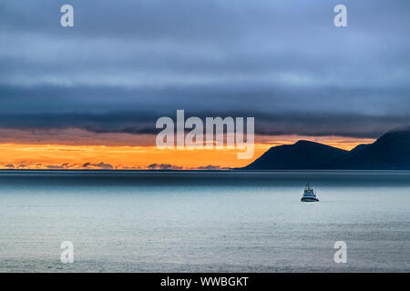 Lo scenario di una piccola nave sul mare di Bering e St Lawrence isola sullo sfondo al tramonto in un giorno di tempesta, Alaska. Foto Stock