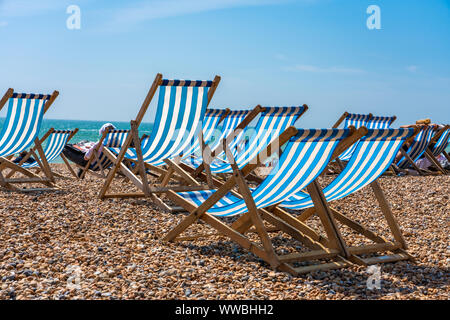 Sedie a sdraio sulla spiaggia di Brighton in una giornata di sole Foto Stock