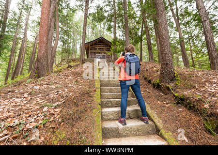 Takayama, Giappone casa in legno santuario in tradizionale Hida non Sato vecchio folk village con gradini, giovane turista fotografo donna prendendo foto del vecchio buil Foto Stock