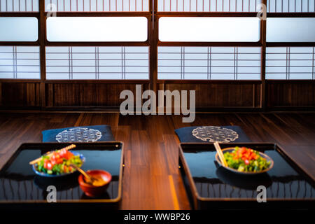 Casa Tradizionale Giapponese o ryokan e sala ristorante con bacchette e due verdi insalata di lattuga piastre su tavola, cuscini cuscino con shoji p di scorrimento Foto Stock