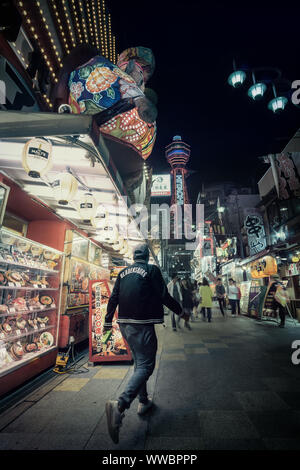 Uomo che cammina fuori del ristorante in Shinsekai, Osaka, Giappone durante la notte. Foto Stock