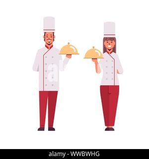 I cuochi giovane chef professionisti tenendo coperto vassoi i vassoi donna uomo ristorante lavoratori in uniforme insieme permanente di cottura degli alimenti concept Illustrazione Vettoriale