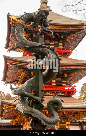 Pagoda Sanju-no-to-Pagoda dell'era Edo a tre piani nel complesso del Tempio Naritasan a Narita, in Giappone, con una statua del drago nel cimitero nel forestiero. Foto Stock
