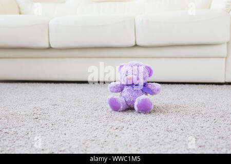 Infanzia e babyhood concetto - Orsacchiotto seduto sul tappeto beige in camera da letto Foto Stock