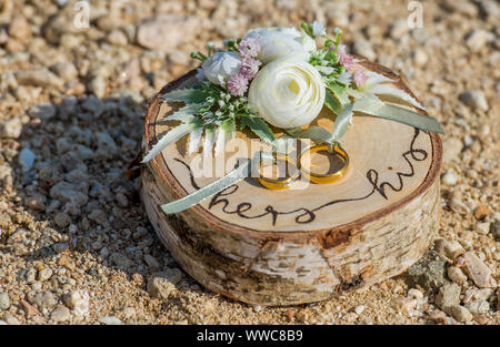 Sposa e lo sposo oro anello di matrimonio con una decorazione legno sulla spiaggia sabbiosa tropicale Foto Stock