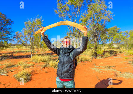 Felice donna turistico tenendo un aborigeno arma di boomerang utilizzato da Luritja Pertame e persone in Australia centrale, Northern Territory. Sabbia rossa in Foto Stock