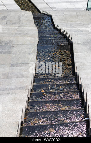 Flusso della città. Cascata d'acqua. Passi verso il basso e nel mezzo, l'acqua fluisce verso il basso le fasi. La moderna progettazione passi. Foto Stock