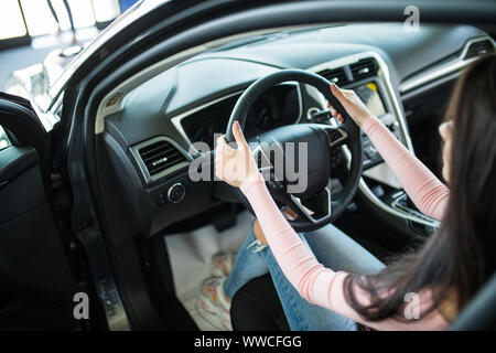 Immagine ritagliata della bella giovane donna alla guida di una vettura e sorridente Foto Stock