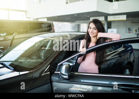 Immagine ritagliata della bella giovane donna alla guida di una vettura e sorridente Foto Stock