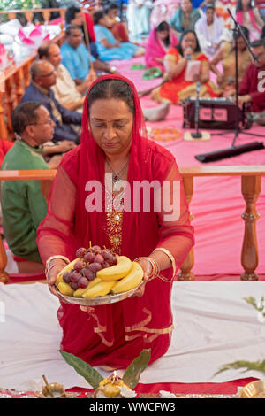 Una pia donna Indù in un sari offre frutta per la divinità a un tempio in Giamaica, Queens, a New York City. Foto Stock