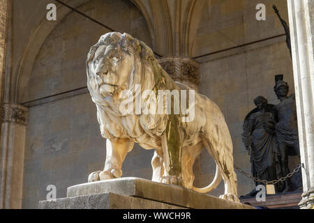 Una delle statue di leoni di fronte Feldherrnhalle (campo esegue il marshalling' Hall), una monumentale loggia all'Odeonsplatz a Monaco di Baviera, Germania. Foto Stock