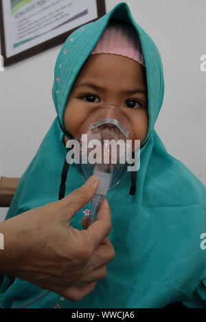 Riau, Indonesia. Xv Sep, 2019. Una ragazza riceve ossigeno trattamento respiratorio dopo essere stata esposta all'haze da un incendio in un bosco presso un centro di salute in Riau, Indonesia, Sett. 15, 2019. Una immagine satellitare rilevato haze spessa da un incendio di foresta in Indonesia diffondersi in stretto di Malacca, di Singapore e della Malaysia il sabato, la meteorologia Indonesiano e geofisica di detta agenzia. Credito: Xinhua/Alamy Live News Foto Stock