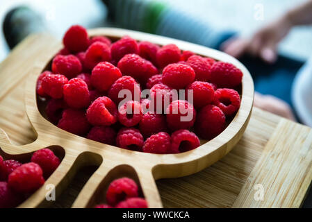 Lamponi freschi accanto al bambino seduto sul divano. baby esplorando la frutta Foto Stock