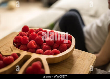 Lamponi freschi accanto al bambino seduto sul divano. baby esplorando la frutta Foto Stock