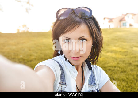 Adulto donna caucasica n natura, tenendo selfie e passeggiate nel parco della sera . selfie Foto Stock