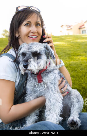 Ritratto di un felice caucasian donna che abbraccia il suo amato cane e parla al telefono.Il concetto di amore per gli animali. migliori amici. Foto Stock