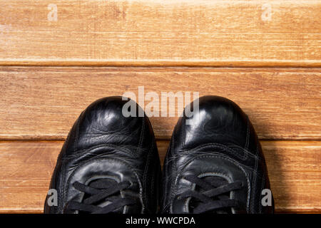 Concetti di Fitness- scarpe da ginnastica su sfondo di legno. Il vecchio affidabile in pelle nero sneakers Foto Stock