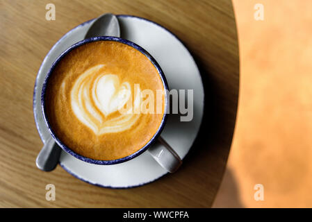 Tazza di cappuccino con latte art su un tavolo di legno. Bellissima schiuma, coppa in ceramica, posto per testo, vista dall'alto Foto Stock