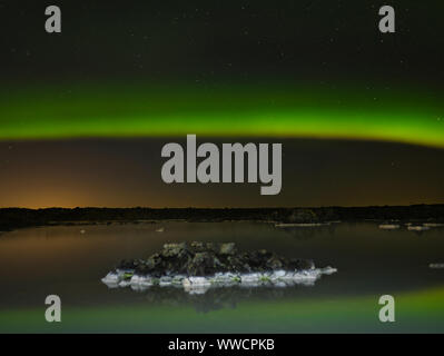 Un Aurora Boreale arco la laguna blu in Islanda Foto Stock