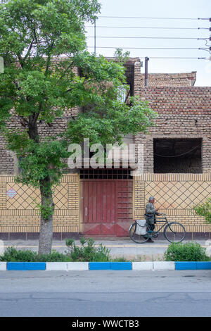 Un uomo che cammina la sua bicicletta in una strada a Kashan, Iran Foto Stock