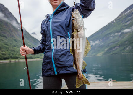 La donna la pesca sulla canna da pesca la filatura in Norvegia. La pesca in Norvegia è un modo per abbracciare lo stile di vita locale. Innumerevoli laghi e fiumi e un extensiv Foto Stock