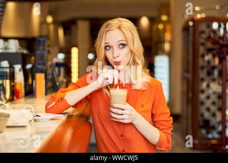 Ragazza giovane di bere il caffè dal tubo bar salotto Foto Stock