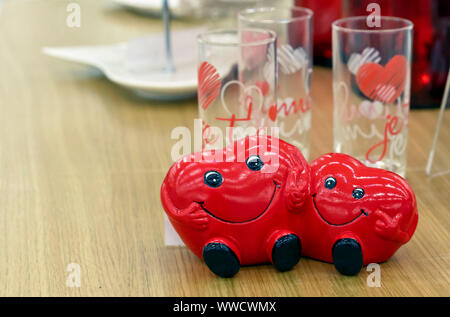 Due cuori sono sorridente e tenendo le mani. Statuetta di ceramica di due cuori. Foto Stock