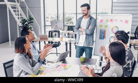 Il direttore creativo team di piombo clap mano con il team di designer al tavolo riunioni.La discussione idea creativa in ufficio Foto Stock
