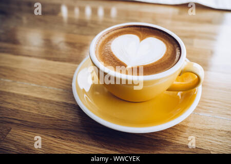 Cappuccino calda tazza di caffè sul vassoio in legno con cuore latte art sulla tavola di legno al cafe,dimensioni Banner di cibi e bevande del concetto. Foto Stock