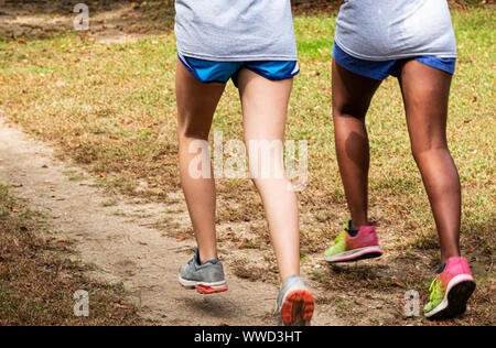 Due ragazze sono la formazione per attraversare il paese in esecuzione su un percorso sterrato in un parco. Foto Stock