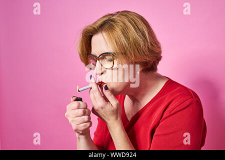 Smoker Ritratto di una vecchia donna di fumare una sigaretta. Isolare su uno sfondo di colore rosso. Foto Stock