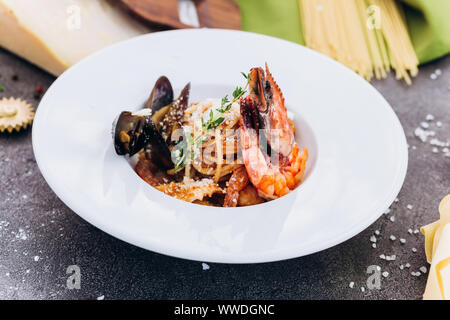 Pasta con gamberoni su sfondo grigio in un piatto bianco. Foto Stock